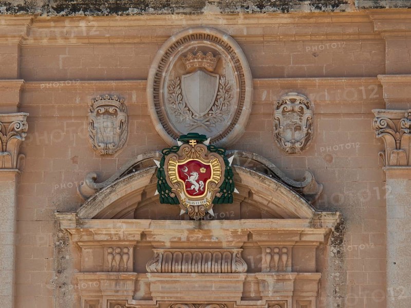 A detailed coat of arms on an old stone wall, surrounded by ornaments and reliefs, the town of mdina on the island of malta with historic houses, colourful balconies, magnificent churches, mdina, Malta, Europe