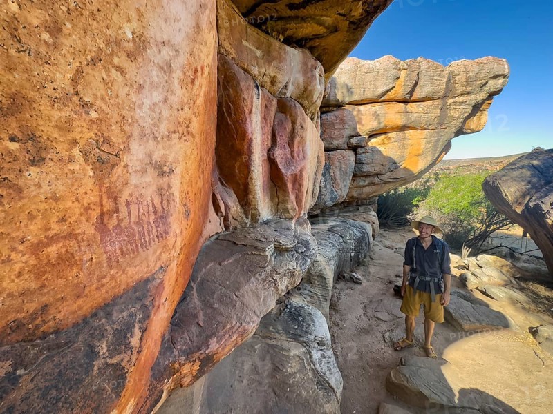 Young man looking at prehistoric depiction of woman on a rock, San rock paintings, Sevilla Art Rock Trail, Cederberg Mountains, near Clanwilliam, Western Cape, South Africa, Africa