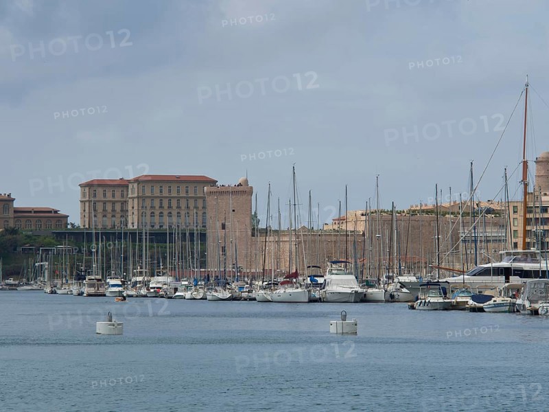 A harbour full of boats and yachts with historic buildings and sailing masts in the background, Marseille on the Mediterranean Sea with the old cathedral and ships in the historic harbour, rocky coast on the mediterranean sea, marseille, france