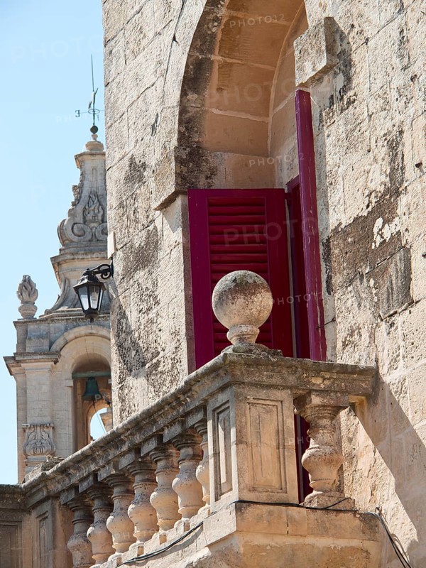Close-up of historic architecture with red shutters and church tower in the background, the town of mdina on the island of malta with historic houses, colourful balconies, magnificent churches, mdina, Malta, Europe