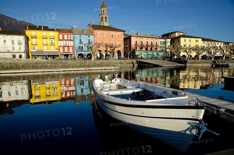 Beautiful City of Ascona on the Waterfront to Lake Maggiore with Reflection and a Boat in a Sunny Day in Ascona, Ticino, Switzerland, Europe