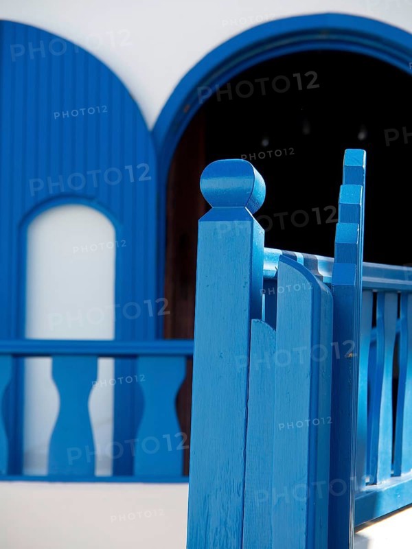 Balcony railings and windows of a house in intense shades of blue, The volcanic island of Santorini with blue and white houses and churches, flowers and palm trees on a volcanic island, santorini, greece