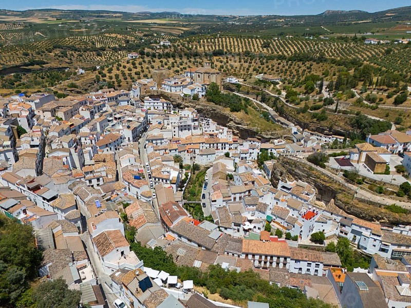 Aerial view of a picturesque town on a hill with serpentine roads and surrounding fields in summer, cave dwellings, Setenil de las Bodegas, Cadiz, Andalusia, Spain, Europe