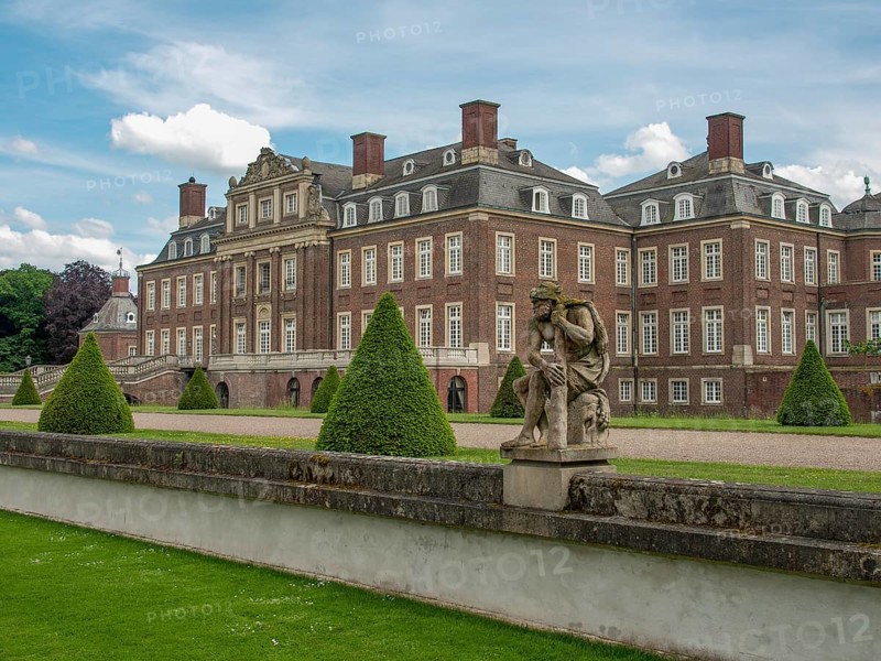 Historic castle with manicured lawn, statues and bushes under a cloudy sky and spacious entrance, historic castle with a green park with sculptures and paths, nordkirchen, germany