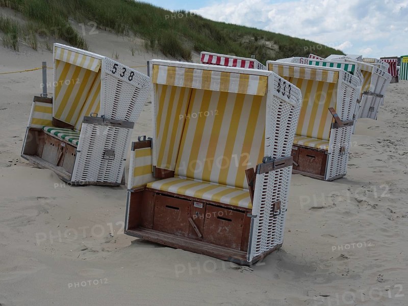 Several beach chairs on the sandy beach with dunes in the background, the north sea island baltrum with grassy dune, colourful beach chairs on the beach and clouds over the sea, Baltrum Germany