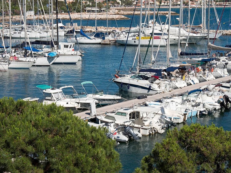 Full marina with many sailing boats and motorboats at the jetty, la seyne sur mer on the mediterranean sea with boats in the harbour, trees and houses on the coast, la seyne sur mer, france