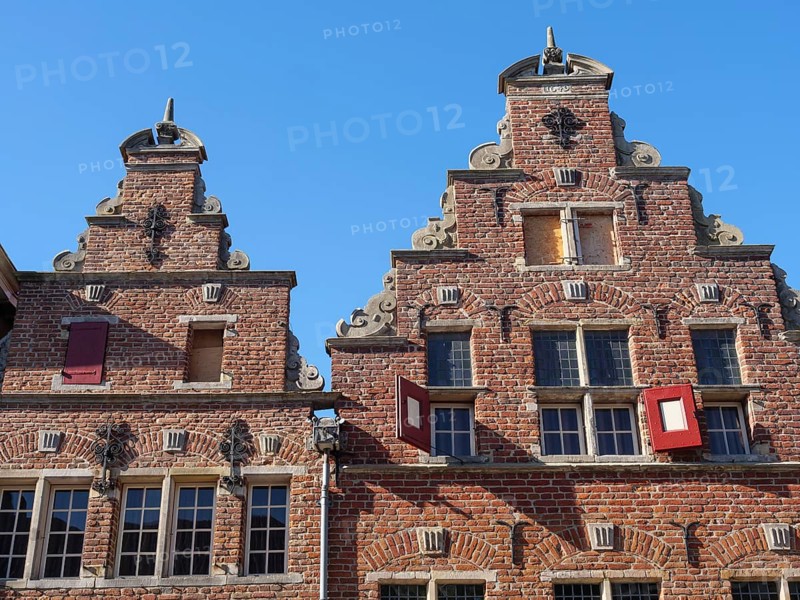 Historic red brick buildings with ornate facades and turrets under a clear blue sky, red brick houses and churches in the Netherlands, Doesburg, Netherlands