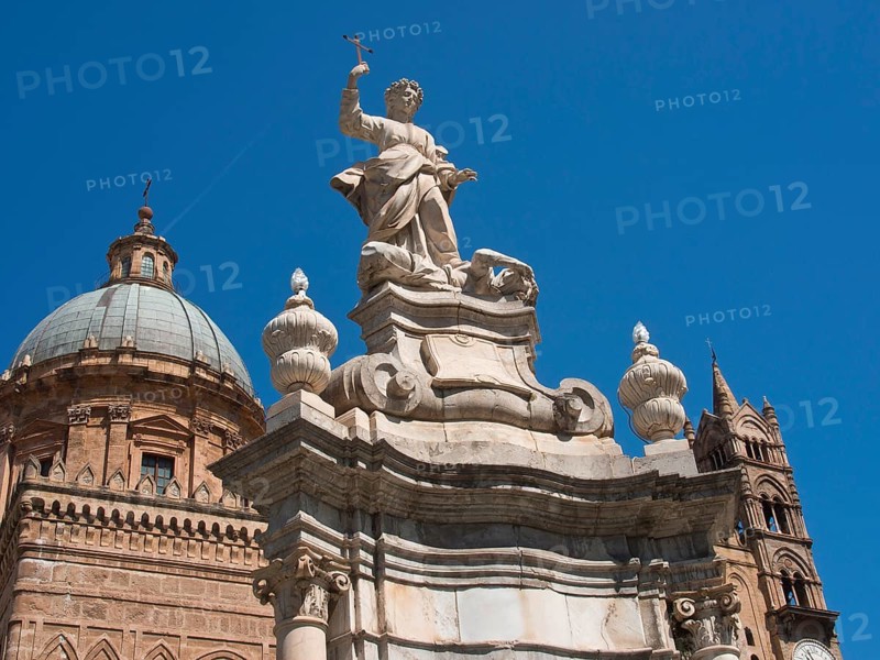 Baroque church structure with dome and stone statue holding a cross, palermo in sicily with an impressive cathedral, monuments and old houses with balconies, palm trees and flowers in italy, palermo, sicily