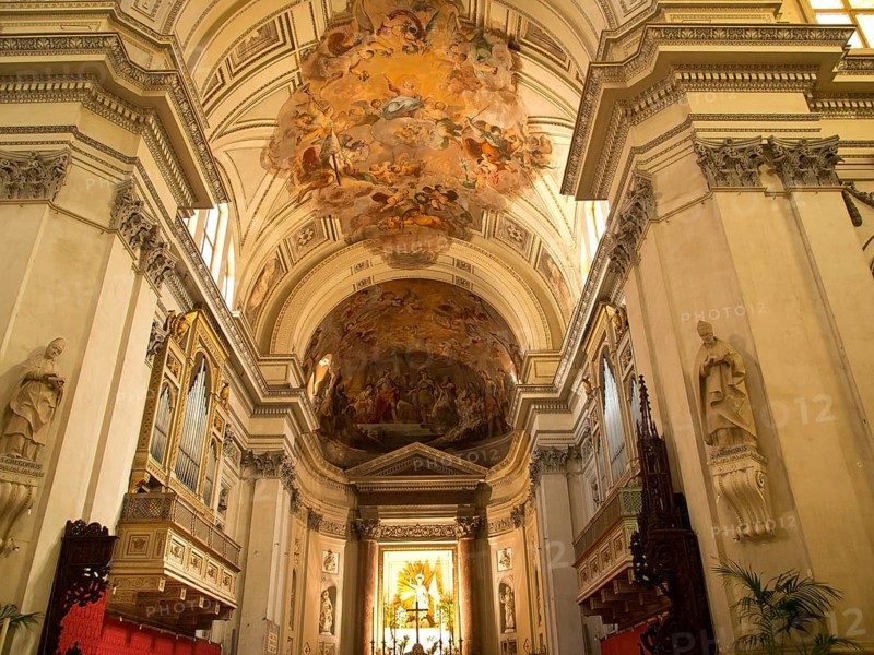 Magnificent church interior with ornate ceiling frescoes and decorative elements in a warm lighting, palermo in sicily with an impressive cathedral, monuments and old houses with balconies, palm trees and flowers in italy, palermo, sicily