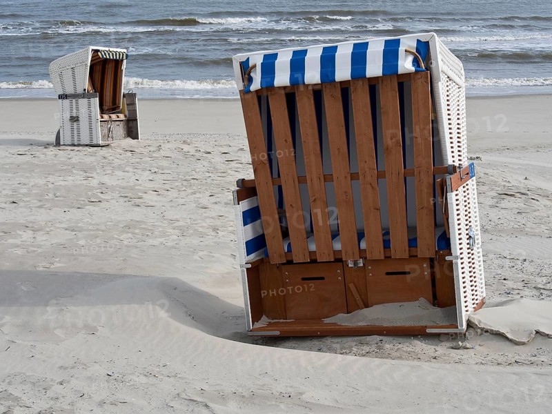 Empty beach chairs on the sandy beach with a view of the calm sea and the slightly cloudy sky, beach chairs on the sandy beach with North Sea waves in the background, wangerooge, Germany, Europe