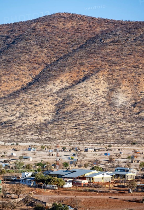 Dry red and white hills in the evening light, houses in the village of Epupa, Kaokoveld, Kunene, Namibia, Africa