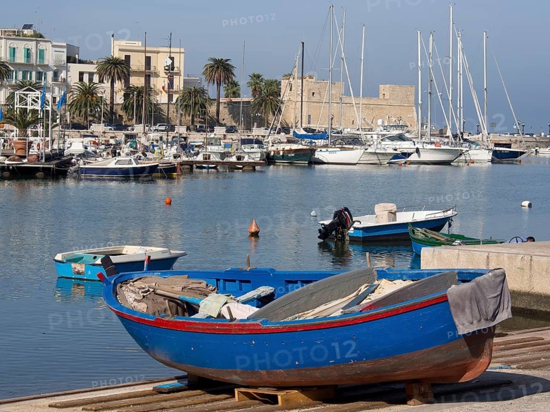 Harbour with fishing boats and sailing boats in the water, palm trees and buildings in the background, The city of Bari on the Mediterranean Sea with historic buildings, small boats in the harbour and beautiful churches, bari, italy