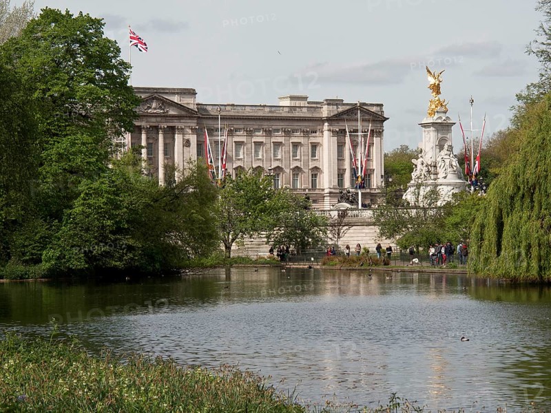 Buckingham Palace and Victoria Monument in the background, in front of it a pond and trees, London, England, Great Britain