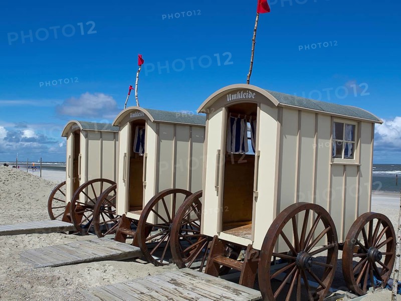 Beige changing cabins with wooden wheels stand on a sandy beach under a blue sky, historic bathing carts on a sandy beach in front of a blue sky, Norderney, Germany, Europe