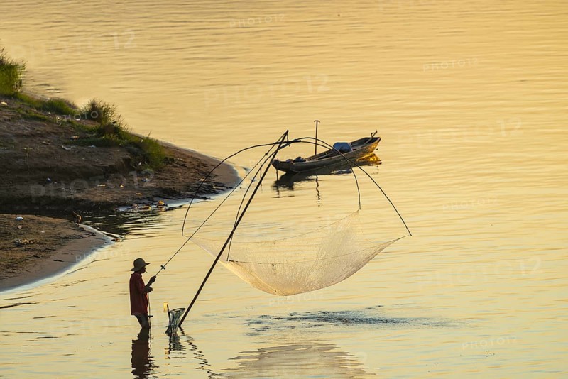 Fisherman with a sinking net at sunset on the Mekong, Luang Prabang, Laos, Asia