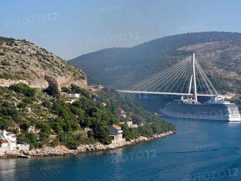 View of a coastline with green hills, a bridge and a cruise ship under a clear blue sky, the old town of Dubrovnik with historic houses, churches, red roofs and fortress walls, dubrovnik, coratia