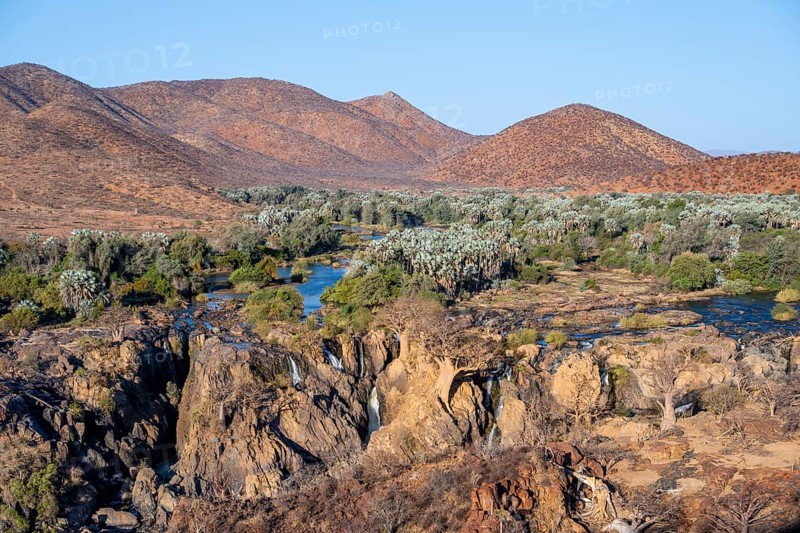 Kunene River with green vegetation in dry red mountain landscape, waterfall and African Baobab (Adansonia digitata), in the evening light, Epupa Falls, Kunene, Namibia, Africa