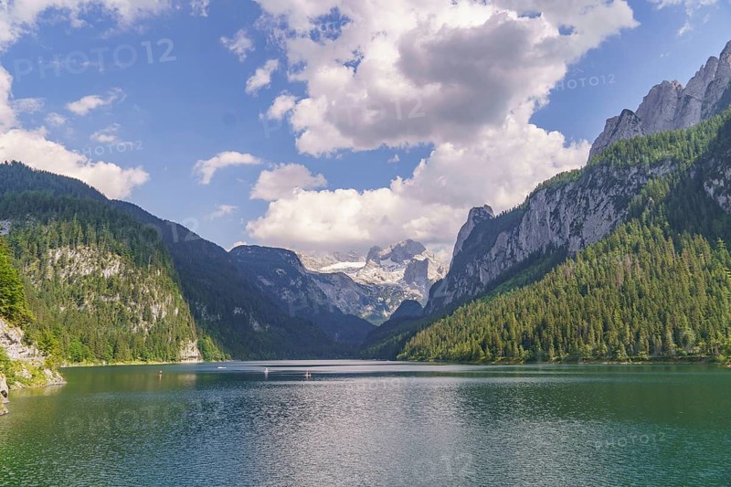 Picturesque lake surrounded by high mountains and forests under a cloudy sky, turquoise green mountain lake with high mountains and green trees in the background, gosau, austria