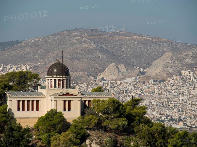 Historic building with a dome on a hill surrounded by trees and urban landscape, Ancient building with columns and trees on the Acropolis in Athens against a blue sky, athens, greece
