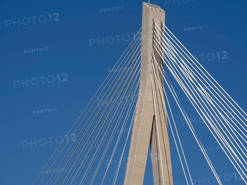 Part of a modern bridge with cable tensions under a clear blue sky, the old town of Dubrovnik with historic houses, churches, red roofs and fortress walls, dubrovnik, coratia
