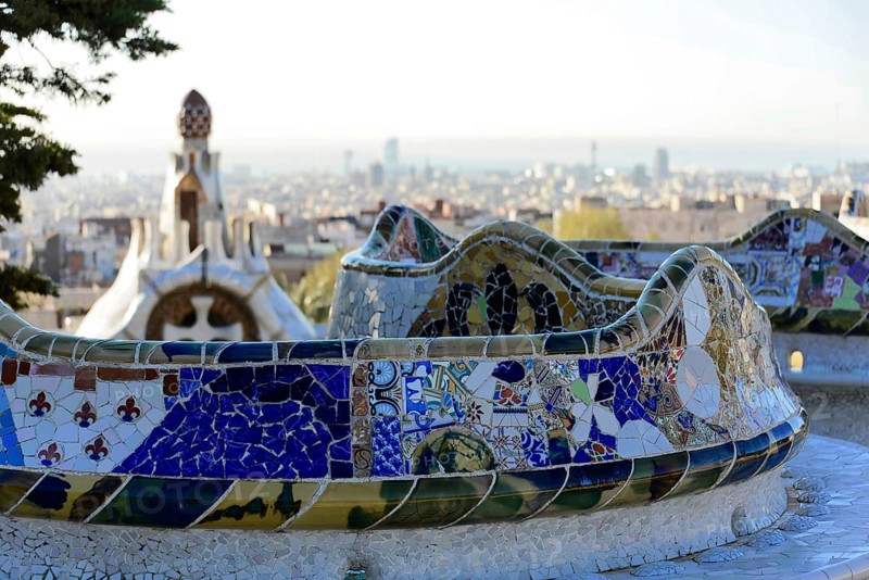 Antoni Gaudi, Park Gueell, UNESCO World Heritage Site, Barcelona, Catalonia, Spain, Europe, Curved mosaic bench in Park Gueell with a view of an extensive urban landscape in the background, Europe