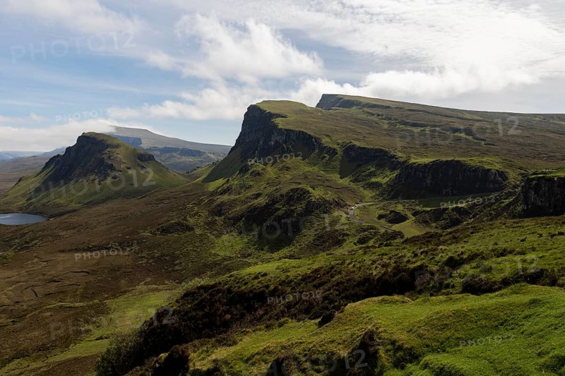 Quiraing, landscape in Scotland, view of rugged mountains and wide plains under a half-cloudy sky