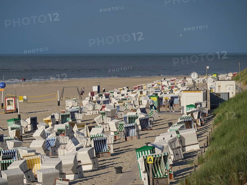 Row of beach chairs along the sandy beach, ideal for beachgoers, the north sea island of baltrum with grassy dune, colourful beach chairs on the beach and clouds over the sea, Baltrum Germany