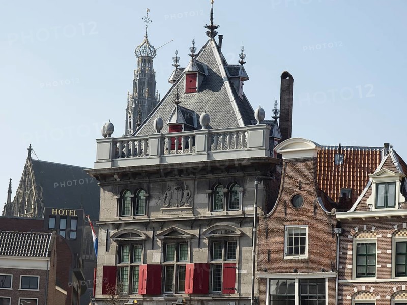 Historic buildings and a church with a hotel in the foreground under a clear blue sky, Haarlem, Netherlands