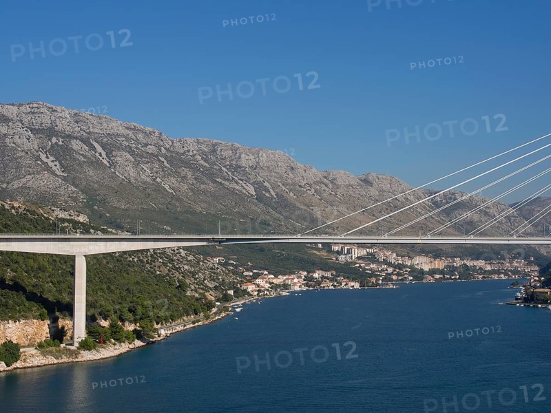 Wide angle shot of a bridge connecting a coastal town with houses and mountains, the old town of Dubrovnik with historic houses, churches, red roofs and fortress walls, dubrovnik, coratia