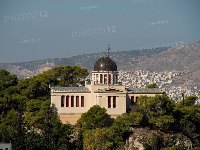 Historic building on a hill surrounded by trees overlooking a city, Ancient building with columns and trees on the Acropolis in Athens against a blue sky, athens, greece