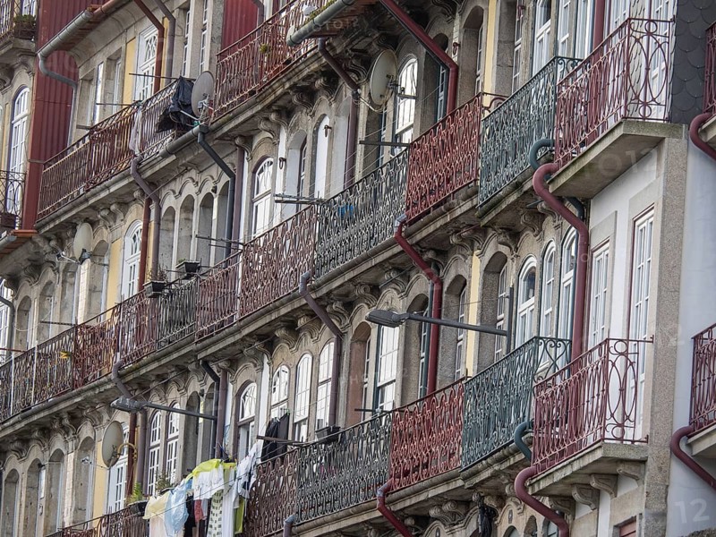 Facades of multi-storey buildings with classic balconies and metal railings, old houses in the historic centre of Porto on the Douro, Porto, portugal