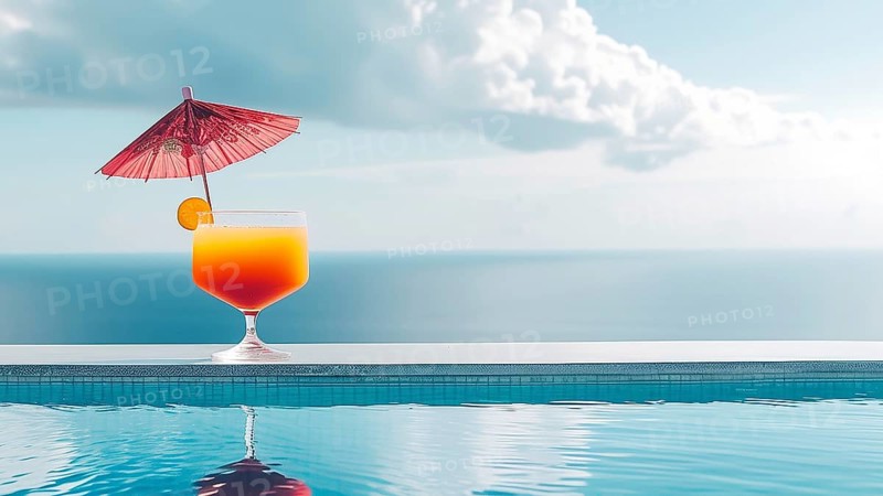 A glass of orange juice with a red umbrella on top of it placed at the edge of a pool, near the ocean, IA generated, AI generated