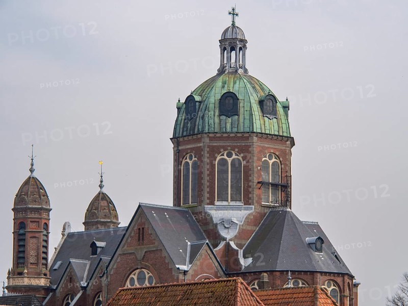 A church building with a central green dome and two smaller towers, under a cloudy sky, historic houses in Hoorn and ships in the harbour, hoorn, the netherlands