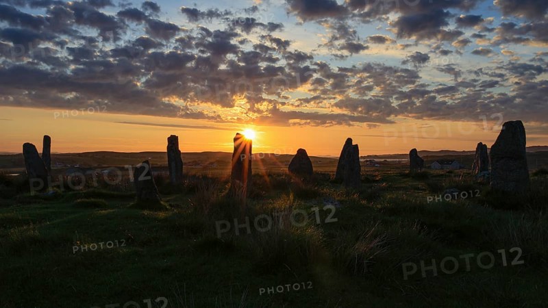 Stone circle at sunset with bright sunlight and clouds in the sky, Isle of Lewis & Harris