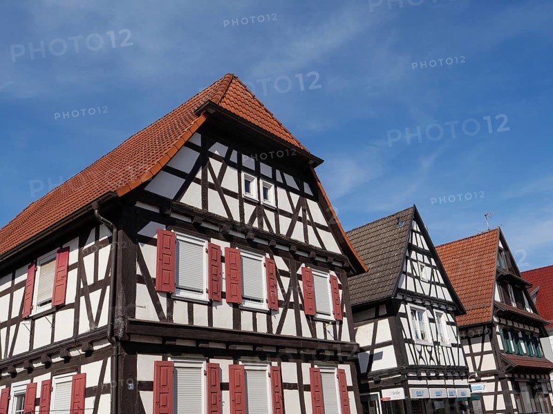 Three half-timbered houses with red shutters and tiled roofs, under a blue sky in the sun, historic half-timbered houses in the Palatinate, kandel, Germany, Europe