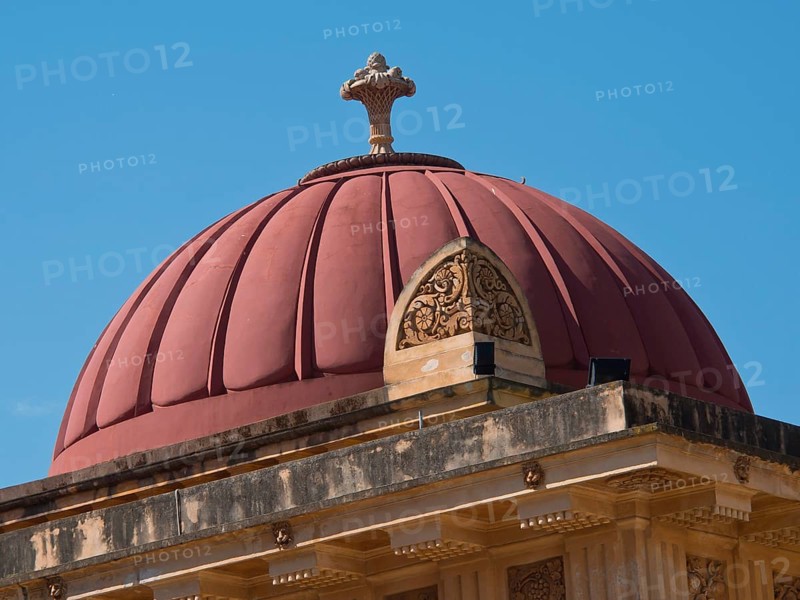 A red dome on a historic building under a clear blue sky, palermo in sicily with an impressive cathedral, monuments and old houses with balconies, palm trees and flowers in italy, palermo, sicily