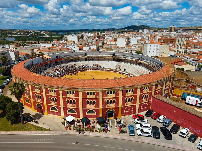 Bullring with red and yellow accents in the middle of a city under a cloudy sky, with parked cars and crowds of people, aerial view, bullfight, Merida, Badajoz, Extremadura, Spain, Europe