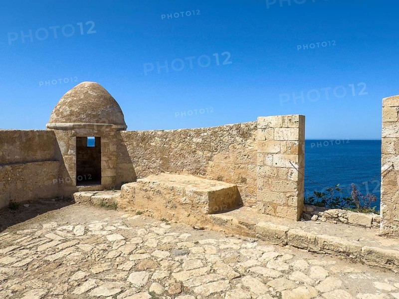 Round watchtower and wall with crenellated gap for guns one of 10 round watchtowers of historic fortress Fortetza Fortezza of Rethymno built by Republic of Venice in 16th century in northwest of old town of Rethymno on rocky hill Paleokastro on north coast of island Crete, in background Aegean Sea Aegean Cretan Sea Mediterranean, Rethymno, Crete, Greece, Europe