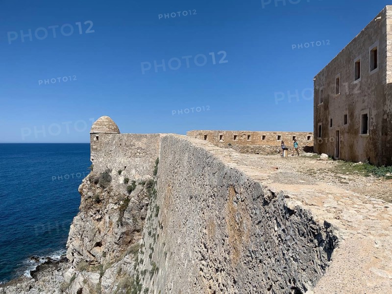 Left round watchtower and fortress wall on Mediterranean coast right part of house of councillors at fortress corner fortress peak Agia Ioustini of historic fortress Fortetza Fortezza of Rethymno built by Republic of Venice in 16th century in northwest of old town of Rethymno on rocky hill Paleokastro on north coast of island Crete, in background Aegean Sea Aegean Cretan Sea Mediterranean Sea, Rethymno, Crete, Greece, Europe