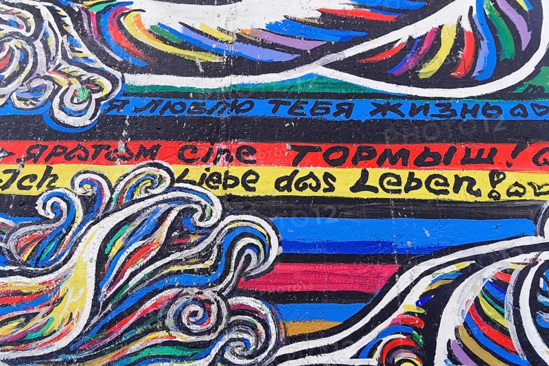Colourful graffiti waves with texts in different languages on a wall, mural, East Side Gallery, Mauergalerie, Berlin, Germany, Europe