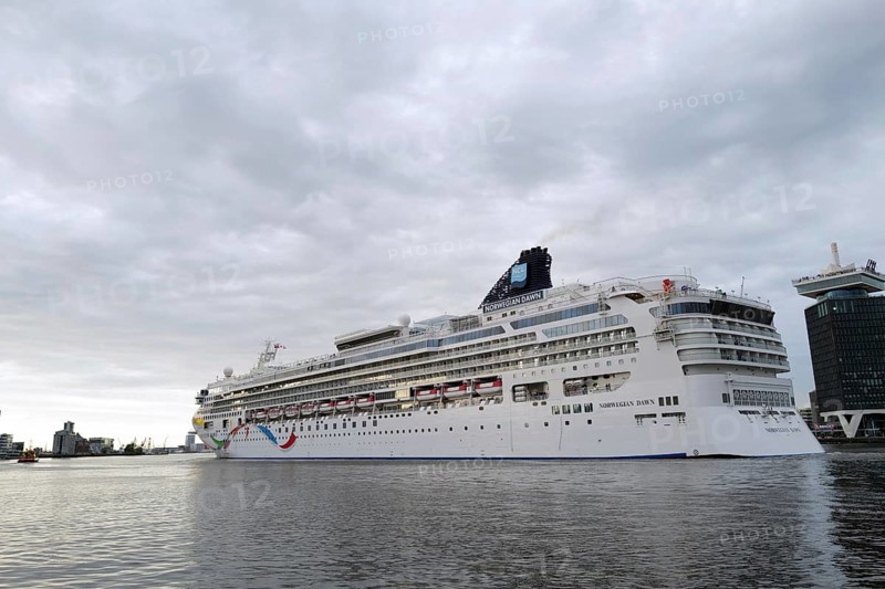 The medium-sized cruise ship the Norwegian Dawn, a ship belonging to the Norwegian Cruise Line, leaves the port of Amsterdam at evening time. Amsterdam, Netherlands