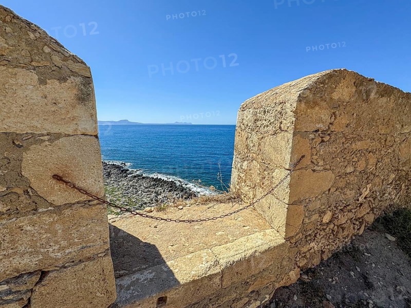 Wall of fortress with battlements gap for guns in historic fortress Fortetza Fortezza of Rethymno built by Republic of Venice in 16th century in northwest of old town of Rethymno on rocky hill Paleokastro on north coast of island Crete, in background Aegean Sea Aegean Cretan Sea Mediterranean, Rethymno, Crete, Greece, Europe