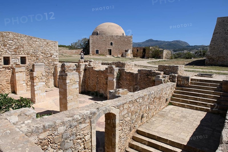 View of exposed walls columns of former storage rooms and stairs to basement of old warehouse in ruins fortress ruins of historic fortress Fortetza Fortezza of Rethymno built by Republic of Venice in 16th century. The ruins of the 16th century fortress in the north-west of the old town of Rethymno on the rocky hill of Paleokastro on the north coast of the island of Crete, on the left in the background the former Sultan Ibrahim Mosque built in 1646, on the right part of the house of the Venetian governor, Rethymno, Crete, Greece, Europe