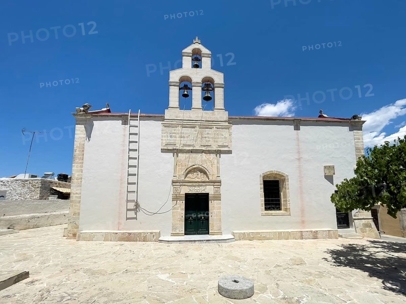Main entrance on the side of Christian Greek Orthodox Church Isodia tis Theotokou in Vori Village church with double apse, in the foreground old millstone on the floor, Vori, Crete, Greece, Europe
