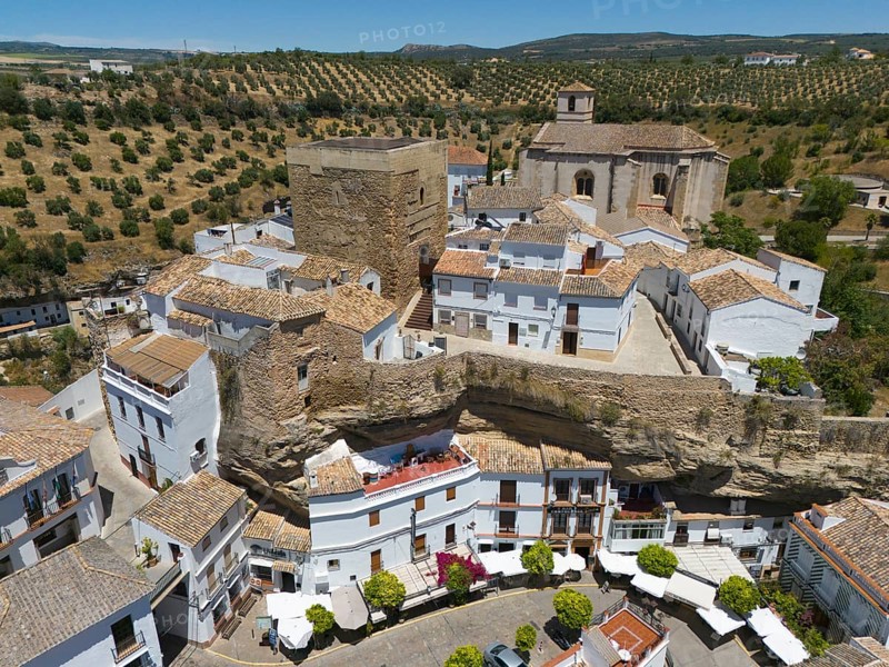 Spanish village with historic buildings, church and olive groves under a sunny sky, surrounded by a stone wall, aerial view, cave dwellings, Setenil de las Bodegas, Cadiz, Andalusia, Spain, Europe