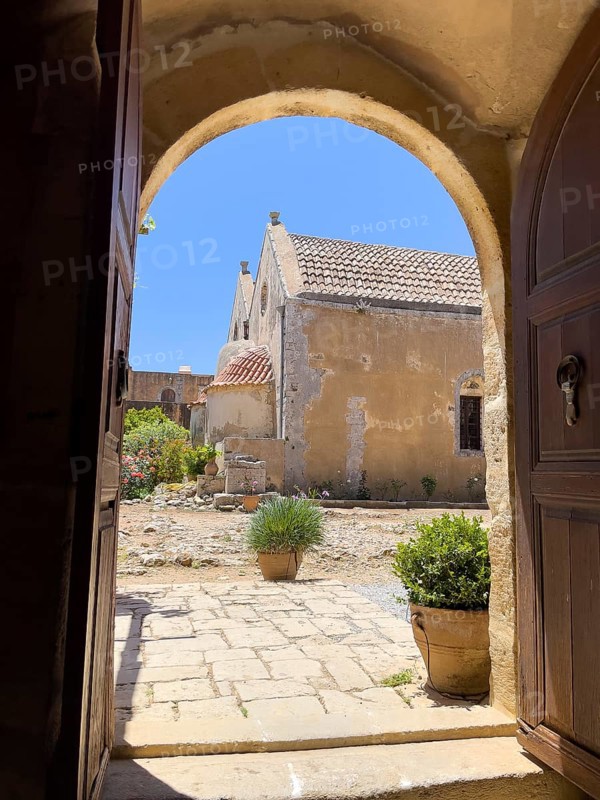 View through door Tor tor archway archway on back of two-aisled church building church monastery church dedicated to Saints Constantine and Helen and Transfiguration Christ the Saviour of Arkadi Monastery with double apse built 1587 to 1600 double apse of UNESCO World Heritage Site Orthodox Monastery Moni Arkadi Arkadi Monastery from early Middle Ages, important national monument national shrine on Crete island, Arkadi, Armnatos, Crete, Greece, Europe