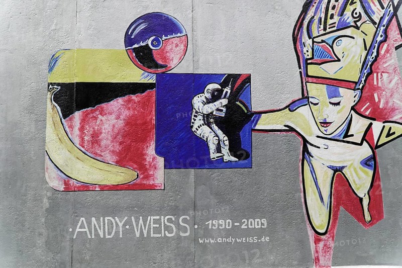 Graffiti on the Berlin Wall in the East Side Gallery, Berlin, Germany, Europe, Colourful graffiti with astronauts and banana on the Berlin Wall, artist's name and years, Europe