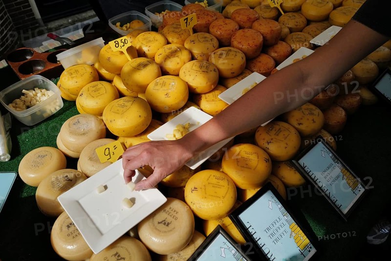A person reaches to sample some Dutch cheese at a cheese market. Alkmaar, Netherlands
