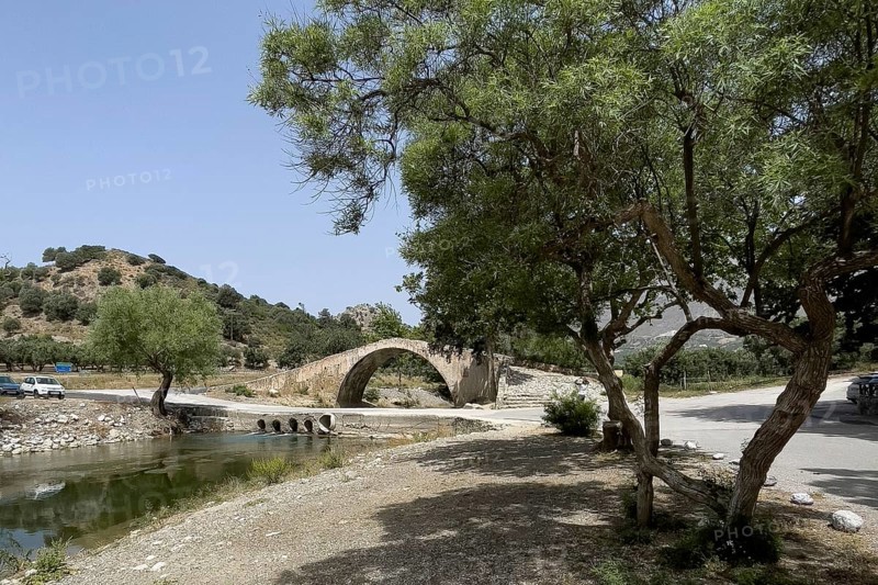 Historic classical arch bridge made of stone in Venetian architectural style Venetian Great Old Bridge 19th century stone bridge built in 1850 in Ottoman times over the middle reaches of the Megalopotamos River near Preveli, in front of it modern flat river crossing with concrete pipes Tubes for water flow, Agios Vasilios, Crete, Greece, Europe