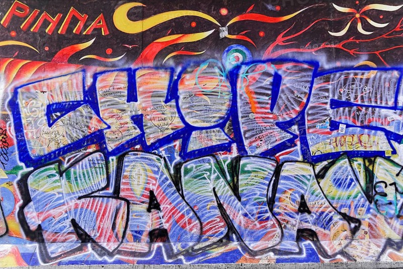 Mural with fiery designs and a large blue graffiti lettering in the foreground, overlaid with text, mural, East Side Gallery, Mauergalerie, Berlin, Germany, Europe